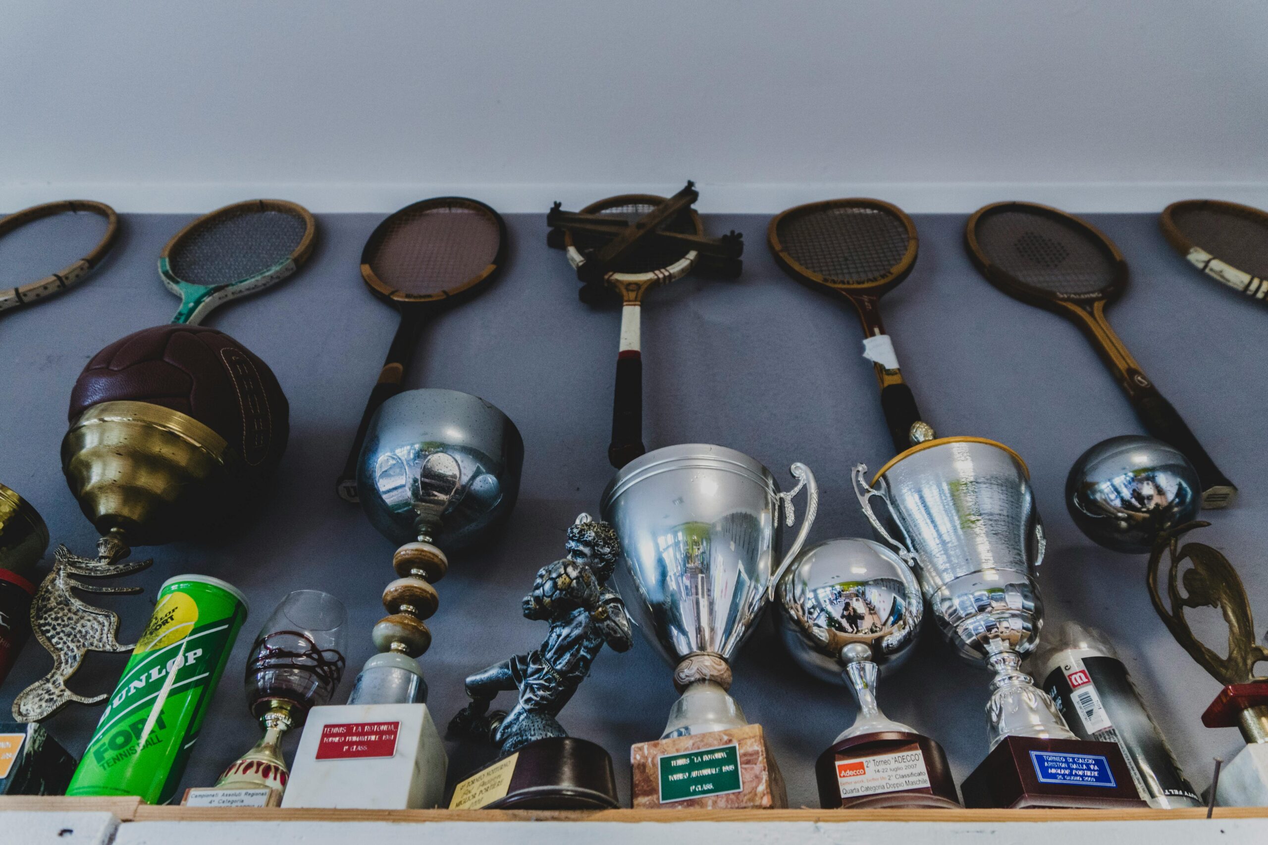 A collection of vintage sports equipment and trophies displayed indoors on a shelf.